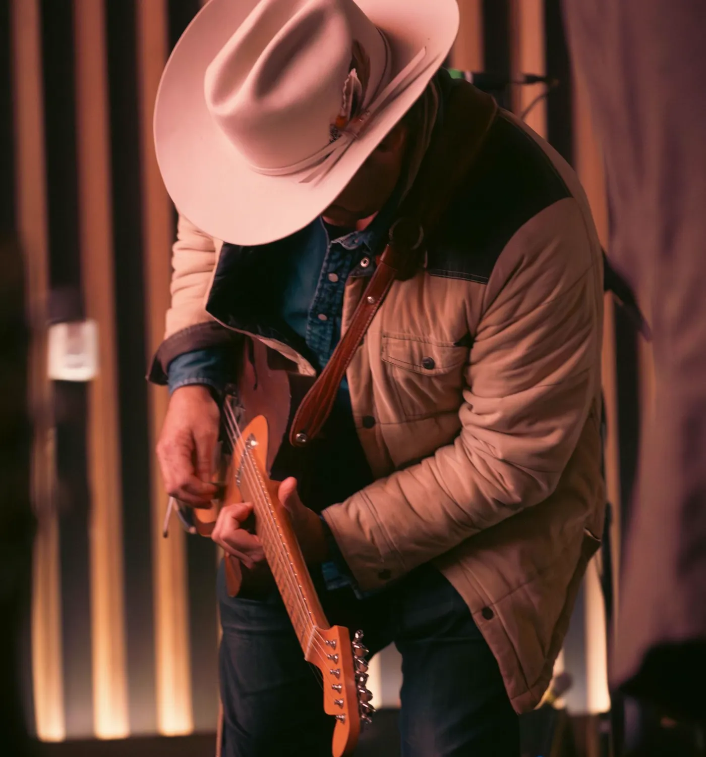 Country singer in a cowboy hat playing guitar on stage